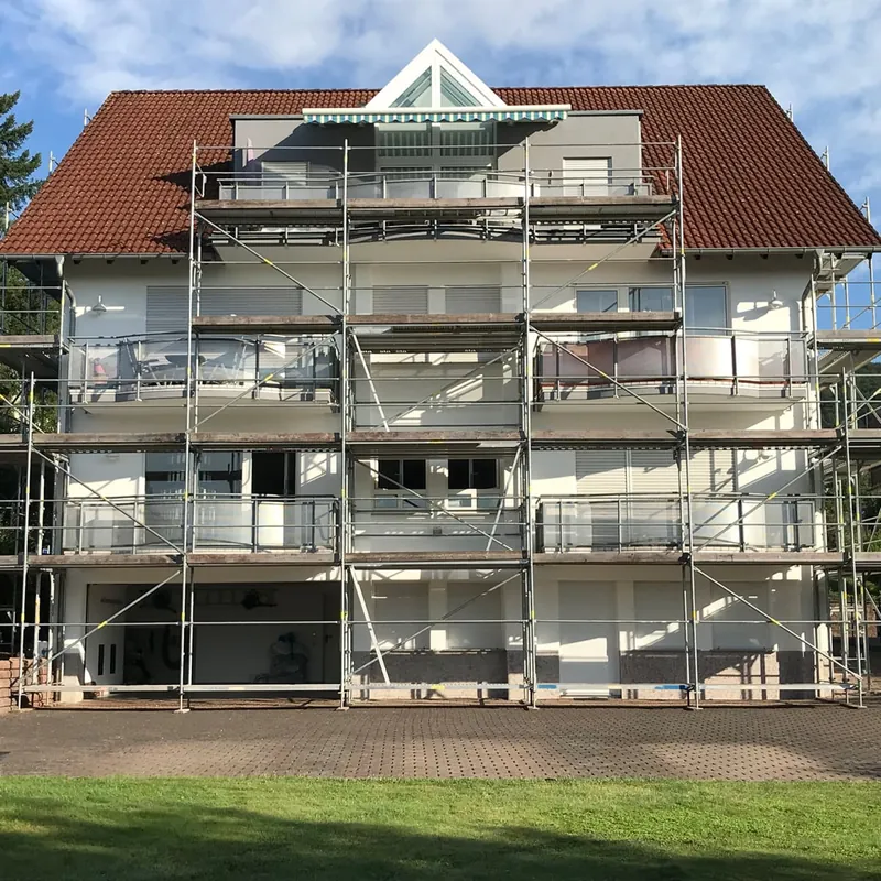 Mehrfamilienhaus mit Ziegeldach und Ziergiebel, Vorderseite vollständig eingerüstet