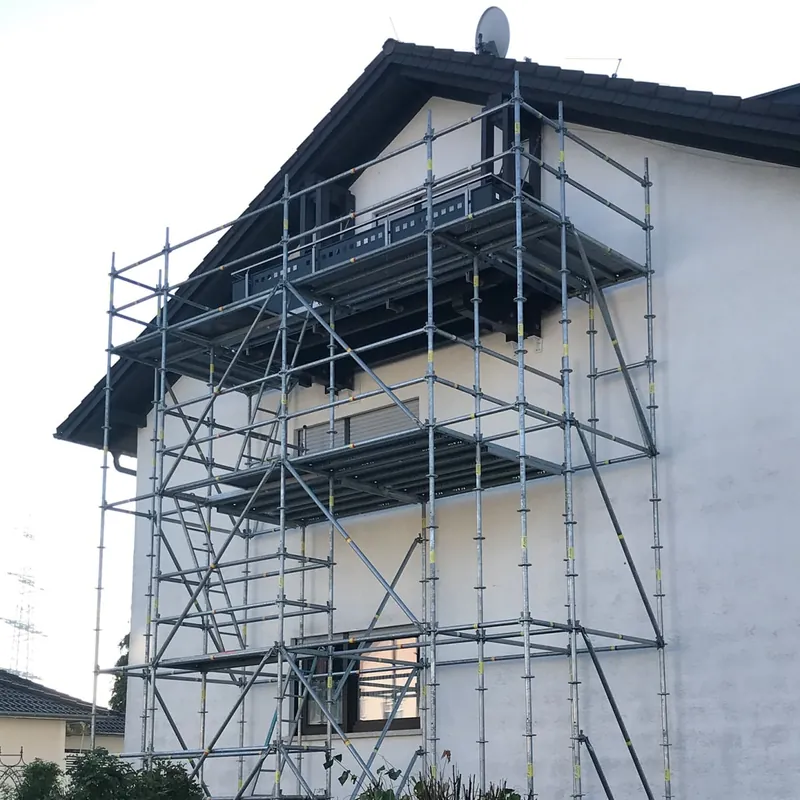 Hell verputztes Wohnhaus mit Gerüst an der Giebelseite für einen Balkonanbau