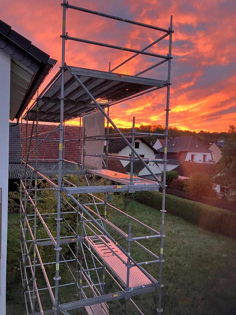 Schmales, mehrlagiges Gerüst an der Giebelseite eines Hauses vor Sonnenuntergang