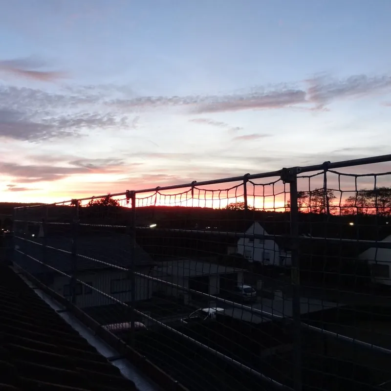 Silhouette eines Gerüsts mit Seitenschutz auf einem Dach im Abendrot