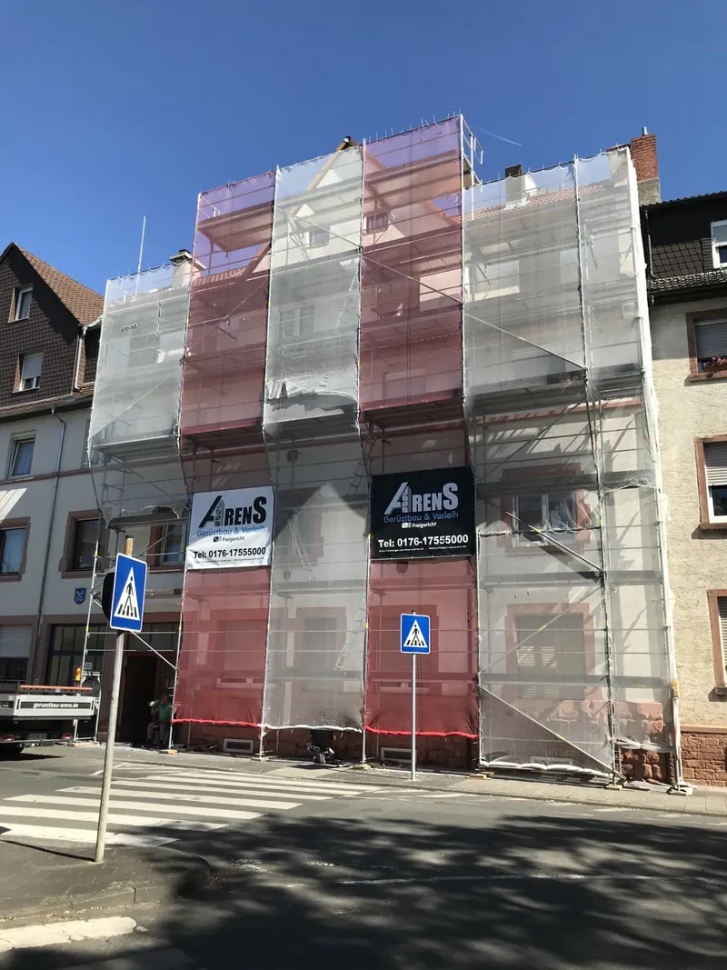Stadthaus an einer Straßenecke, komplett mit rot-weißer Plane eingerüstet