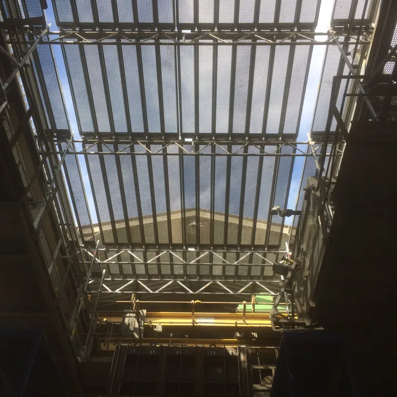 Blick von unten in ein Gerüst unter einem großen Glasdach in einer Halle